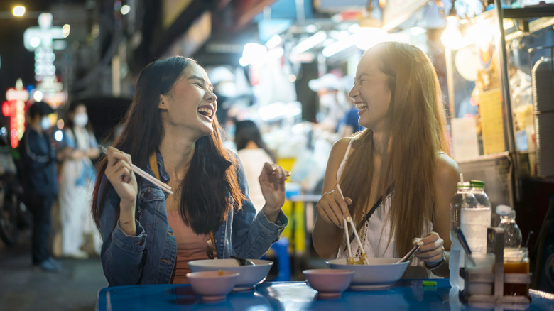 Women eating together at night in Bangkok street market