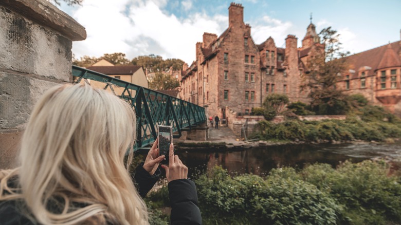 Woman taking photo of historic building in Edinburgh