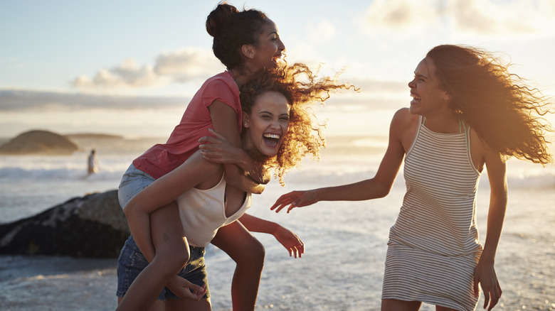 Young women playing on beach at sunset