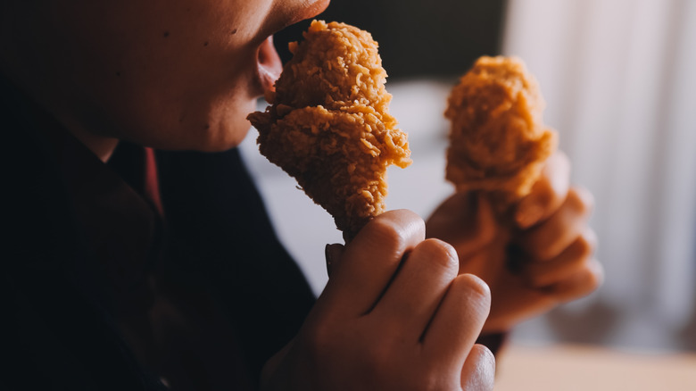 Person biting fried chicken drumstick