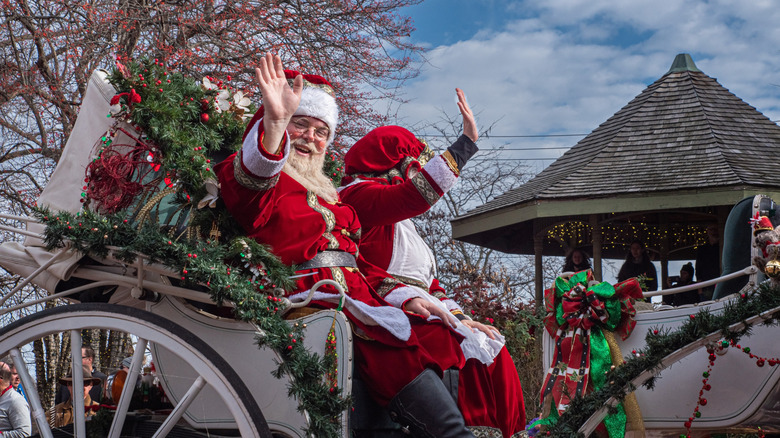 Santa and Mrs Claus while waving crowd from a horse drawn carriage