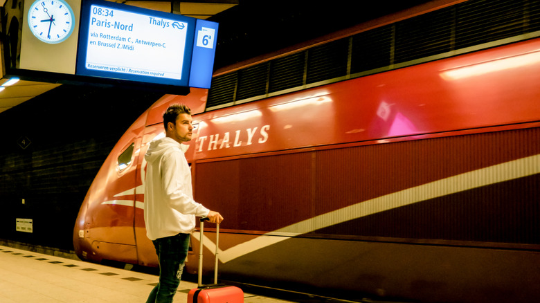 Male traveler waiting on the platform with a Thalys train in the backdrop