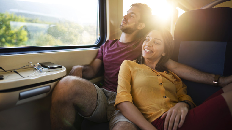 A couple traveling on a high-speed train looking out the window.