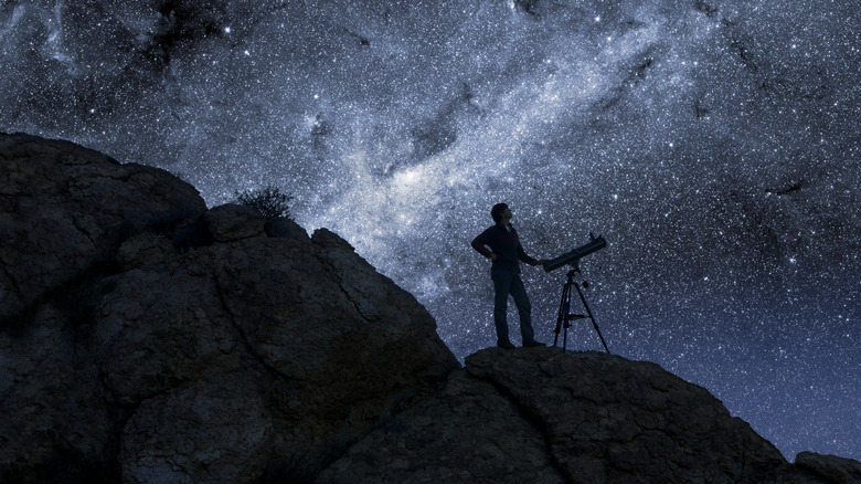 Man with telescope in front of Milky Way