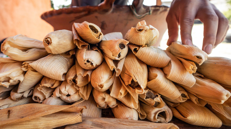 Hand touching a stack of tamales