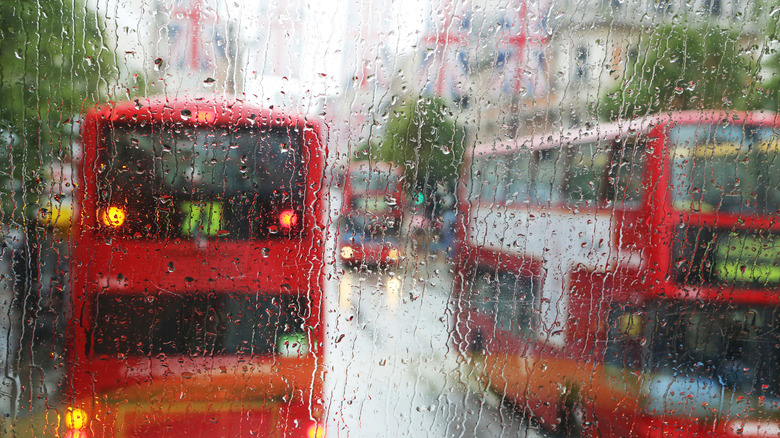 Red double-decker buses in London seen through a rain-streaked window