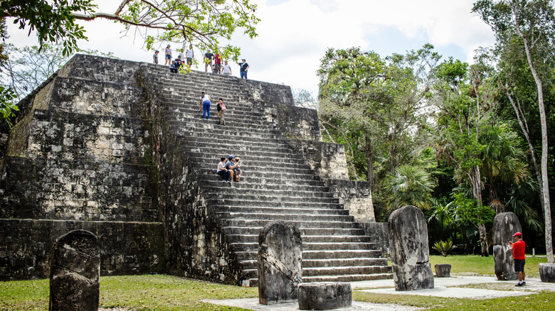 People climbing ancient stone structures in Tikal, Guatemala