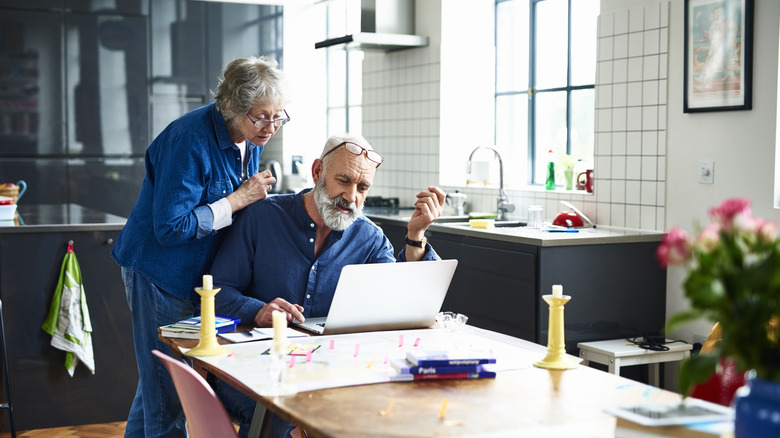 couple planning travel online with maps on table