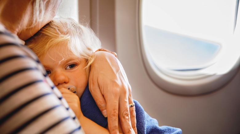 Mom hugging scared child on plane