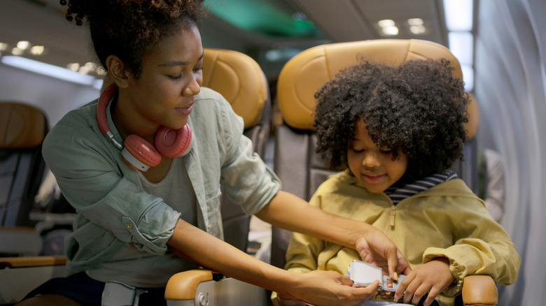 Woman buckling kid's seatbelt on plane