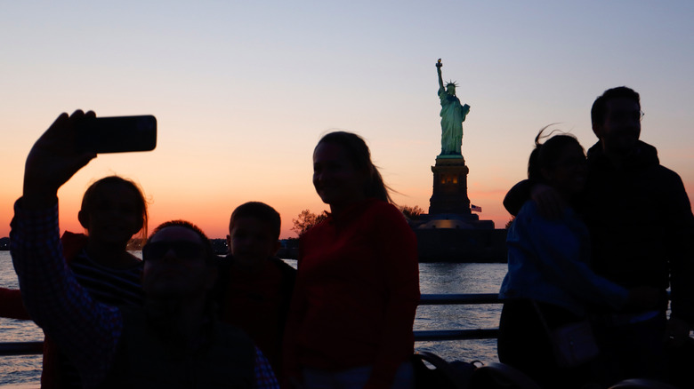 Tourists on a sightseeing cruise look at statue of liberty