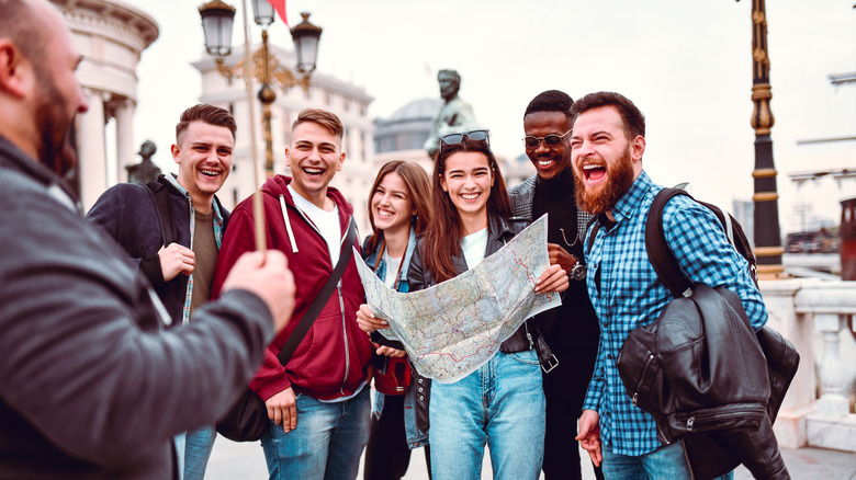 Small group of tourists in European city laughing with tour guide