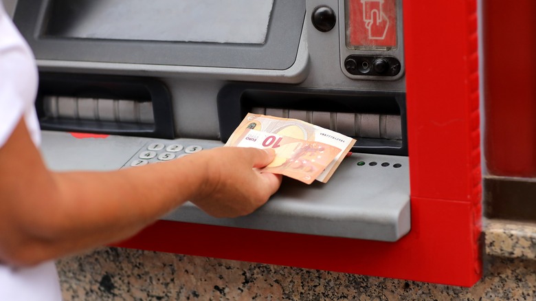 A person withdrawing Euros from an ATM machine