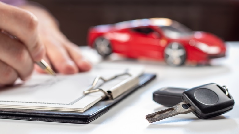 Person signing paperwork and car keys