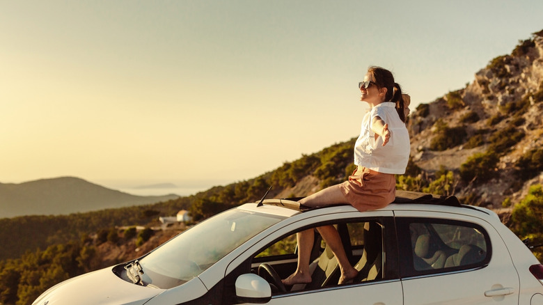 Woman relaxing on top of car