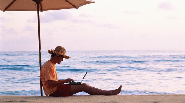 Man working on computer on beach