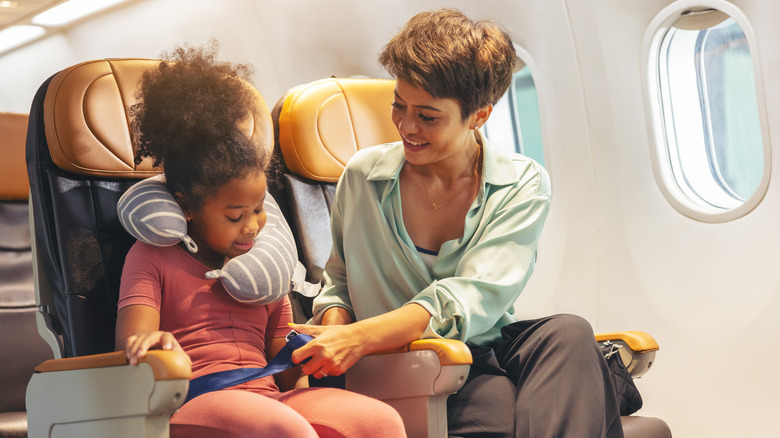 mom buckling child into flight