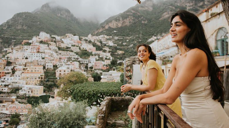 Two woman stand side by side against a railing in Amalfi Coast