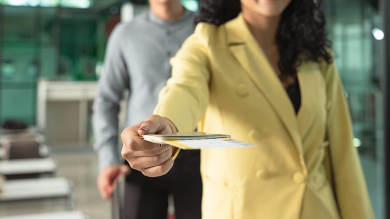 A person handing their passport to a gate agent