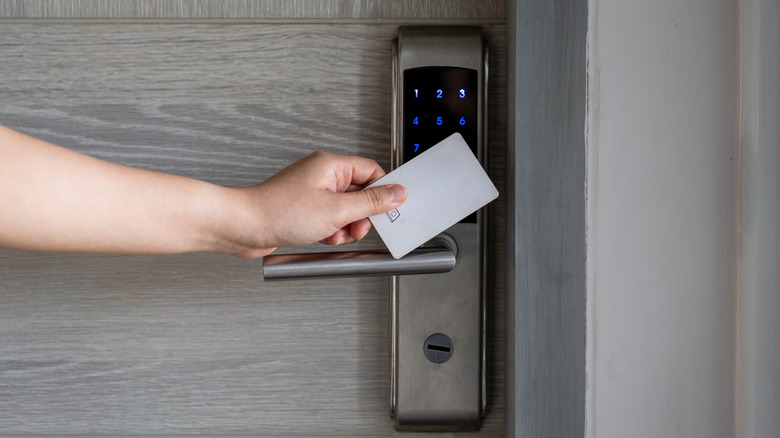 Person waving hotel key card in front of door