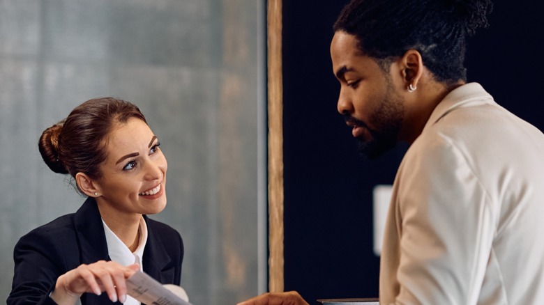 A hotel desk employee helping a man check in