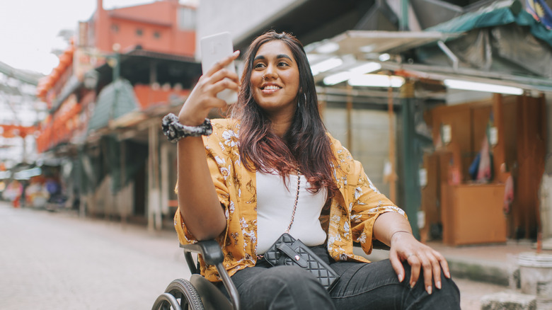 A wheelchair user takes a selfie on the street