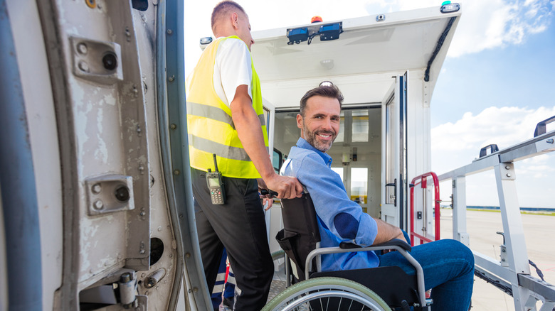 A wheelchair user gets assistance boarding a plane