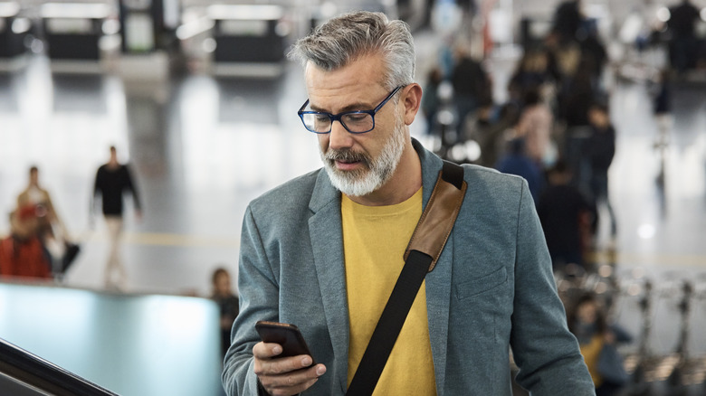 A man in an airport uses his phone