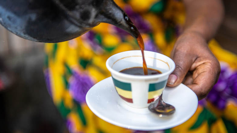 Woman pours coffee into a white cup in Addis Ababa, Ethiopia