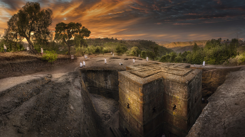 Pilgrims at the San Jorge Church in Lalibela, Ethiopia under an orange sky