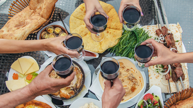 Hand holding wine toasting over Georgian feast