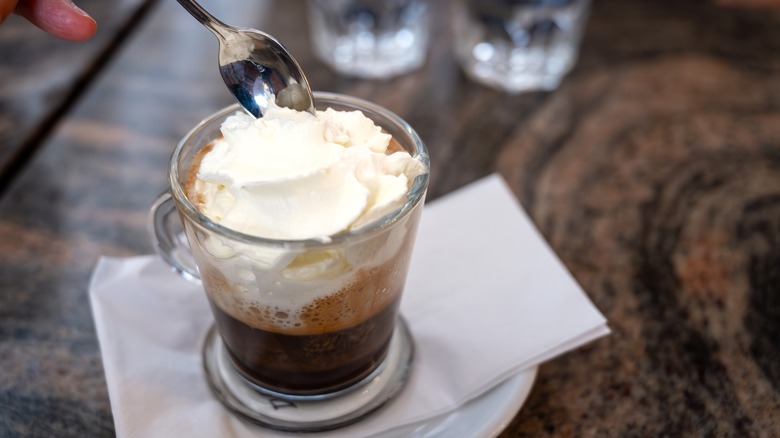 A coffee topped with whipped cream sitting on a marble table