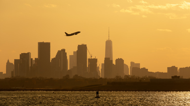 A plane flying over NYC, leaving LaGuardia Airport at sunset