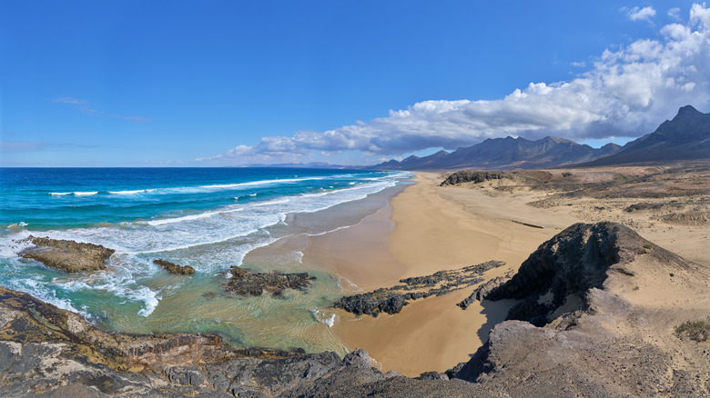 Empty beach ringed by mountains on a clear day