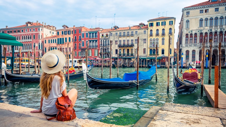 Woman sitting by canal, Venice, Italy