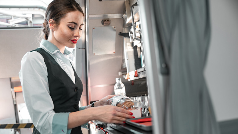 A flight attendant getting items from a galley on a plane