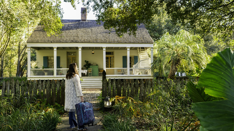 Woman arriving to a quaint cottage surrounded by greenery, Breaux Bridge, Louisiana