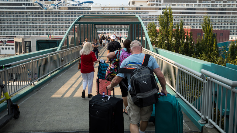 Passengers embark on a cruise ship with their luggage