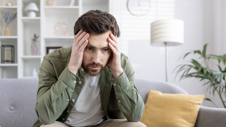 Man sitting on couch with his head in his hands