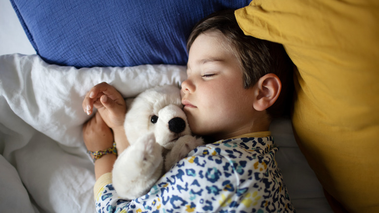 Boy sleeping with stuffed bear