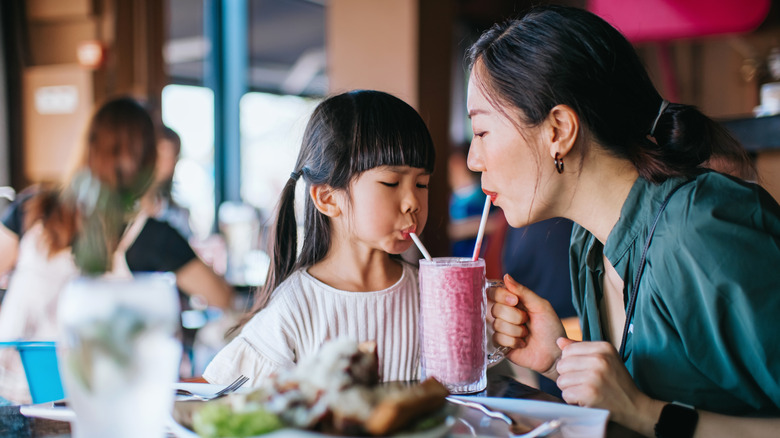 Mother and daughter sipping smoothie