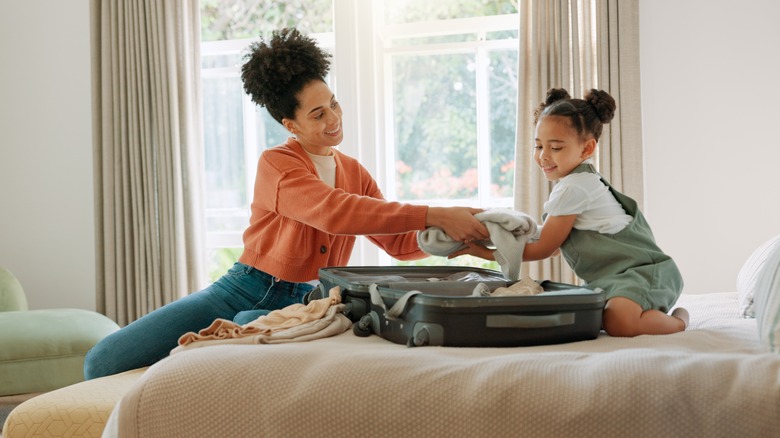 Mother and daughter packing suitcase