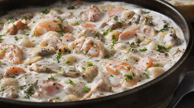 close up on a black bowl of creamy, chunky New England seafood chowder