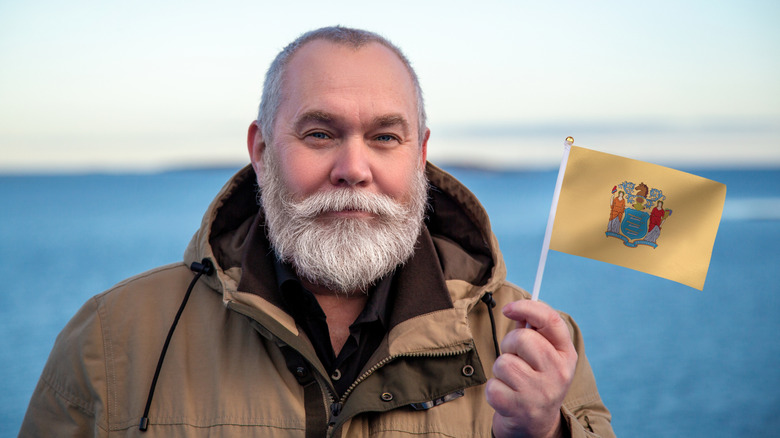 Older man holding a New Jersey state flag