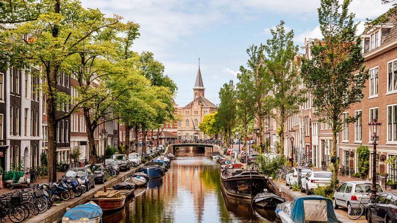 Canal lined by historic buildings and church in the background