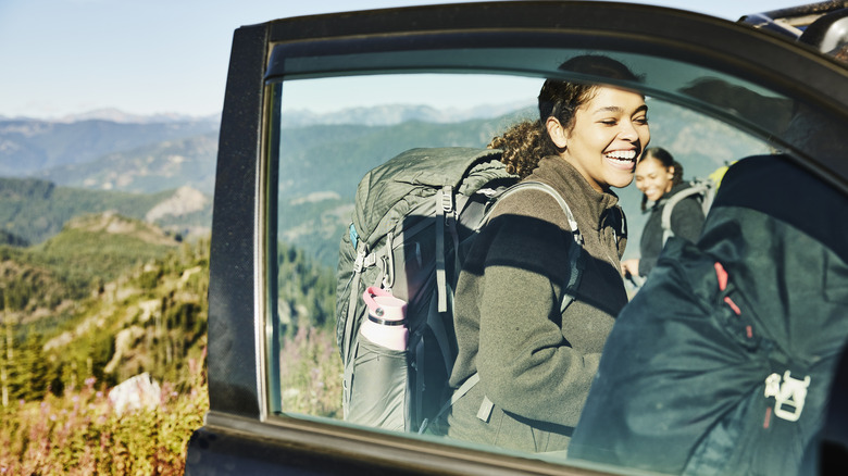 A hiker with a backpack loads up the car after a nature hike