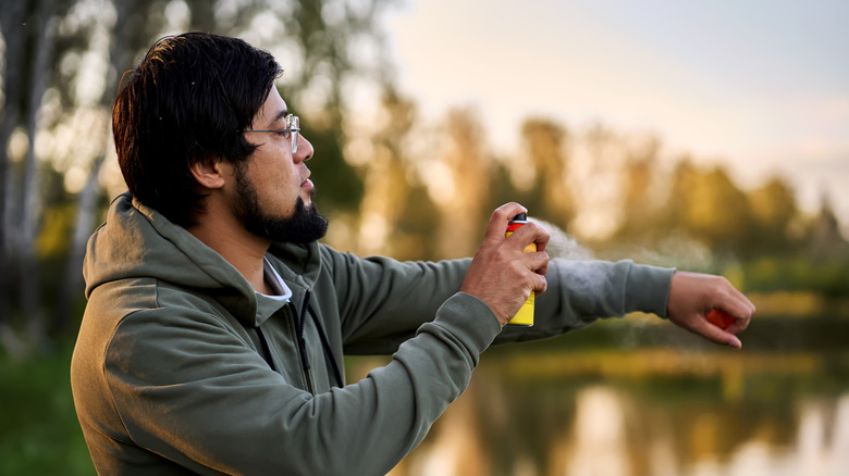 A Hiker sprays himself with insect repellent