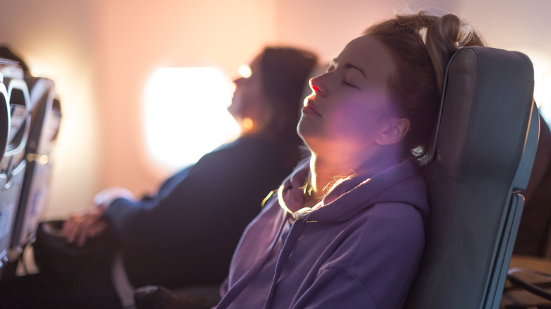 Passengers sleeping in the aisle and window seats on a plane