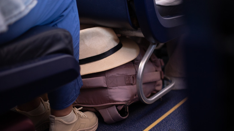 Someone's bag and hat under the plane seat in front of them