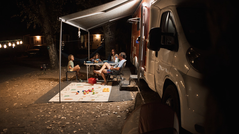 Family hanging out outside RV at night
